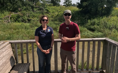 woman and man standing on boardwalk with wooden fence next to springs